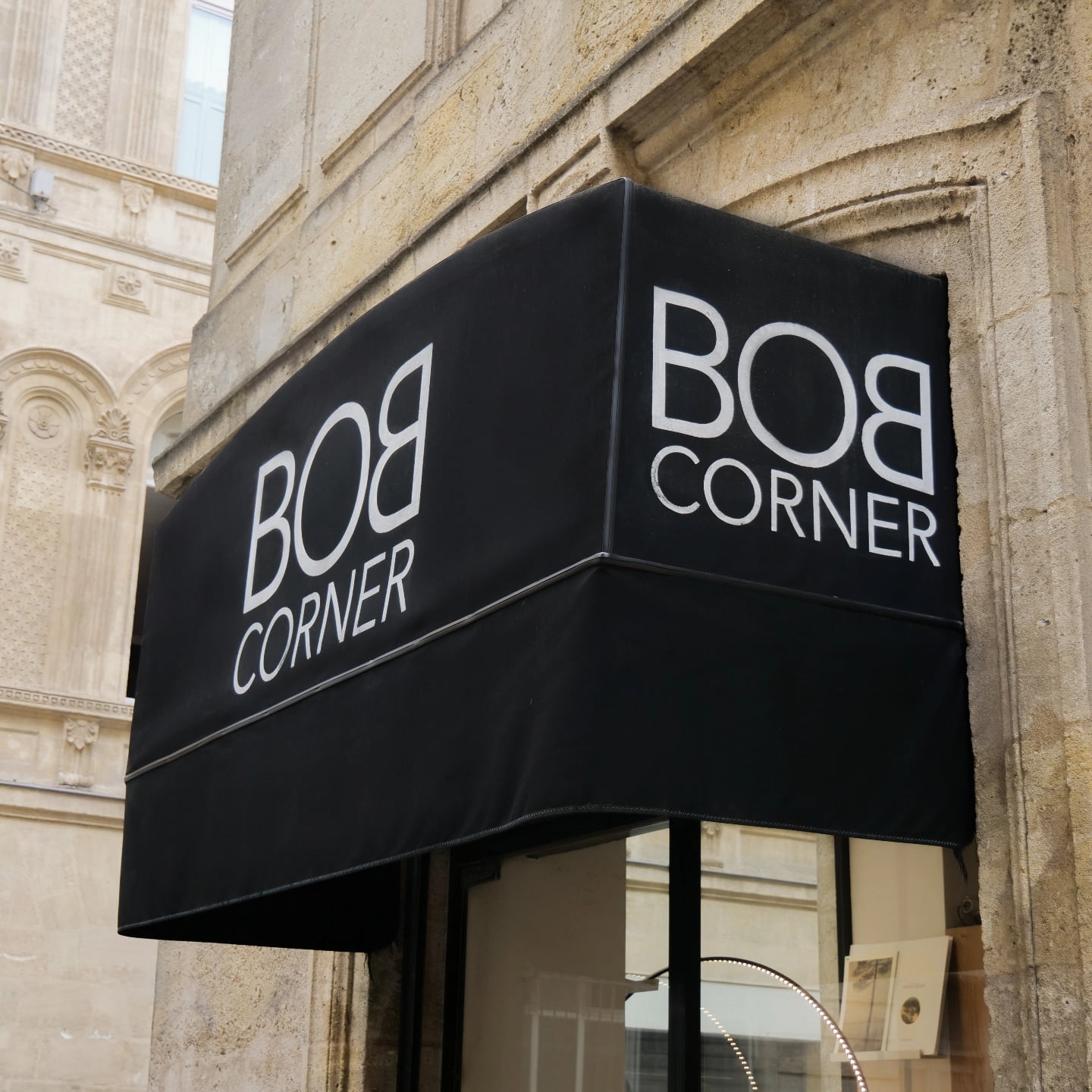 Rue pavée ensoleillée du centre-ville de Bordeaux avec façades en pierre typiques, vélos et piétons – ambiance urbaine chic près de la boutique Bob Corner, concept store décoration